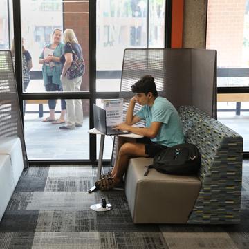 A student studies his computer at a bench in the CoLab.